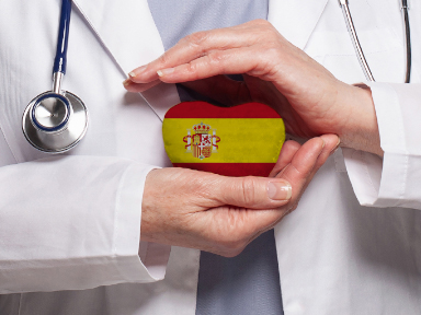 Profesional sanitario con una bandera de España en forma de corazón entre las manos