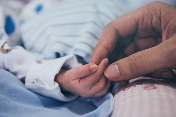 Mano adulta cogiendo la manita de un bebé
