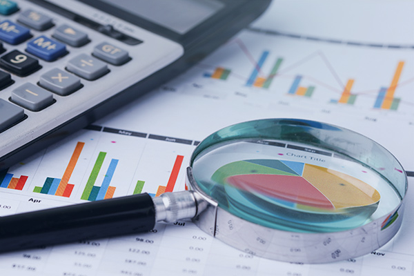 Lupa y calculadora encima de una hoja con gráficas